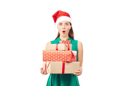 Portrait of young womanin Santa hat holding stack of Christmas gifts on white backgroundの写真素材