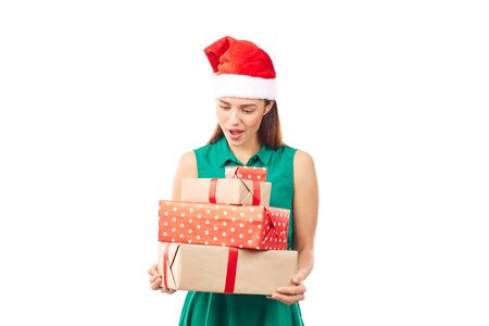 Portrait of young womanin Santa hat holding stack of Christmas gifts on white backgroundの写真素材