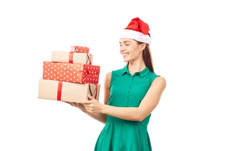 Portrait of young womanin Santa hat holding stack of Christmas gifts on white backgroundの写真素材