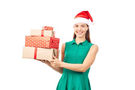 Portrait of young womanin Santa hat holding stack of Christmas gifts on white backgroundの写真素材