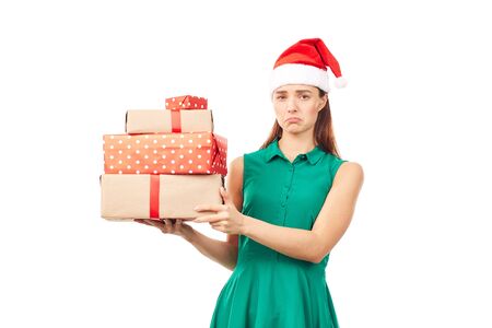 Portrait of young womanin Santa hat holding stack of Christmas gifts on white backgroundの写真素材