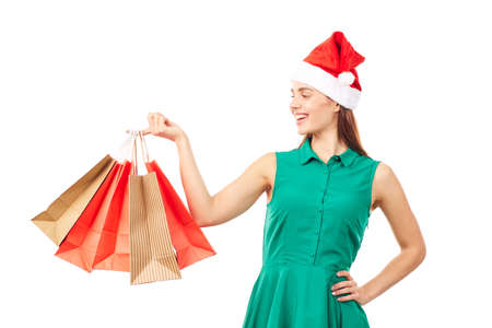 Studio portrait of young woman in Santa hat posing with shopping bags on white backgroundの写真素材