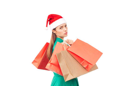Studio portrait of young woman in Santa hat posing with shopping bags on white backgroundの写真素材