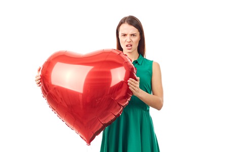 Young woman holding big heart shaped balloon on white backgroundの写真素材