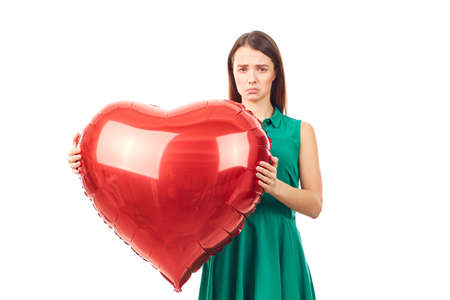 Young woman holding big heart shaped balloon on white backgroundの写真素材