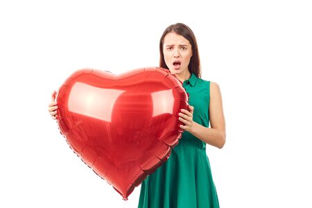 Young woman holding big heart shaped balloon on white backgroundの写真素材