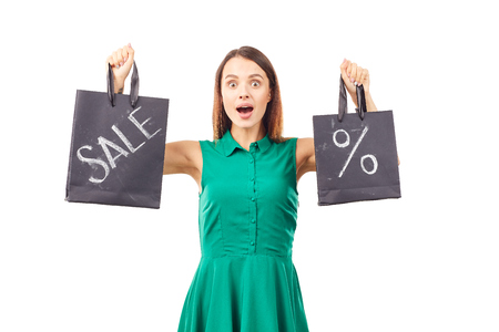 Portrait of female shopaholic holding shopping bags with sale/discount signの写真素材