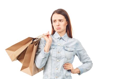 Portrait of young woman in denim jacket holding shopping bags on white backgroundの写真素材