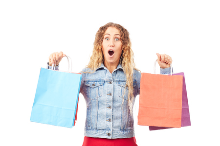 Portrait of young woman in denim jacket holding shopping bags in both handsの写真素材