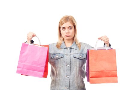 Portrait of young woman in denim jacket holding shopping bags in both handsの写真素材