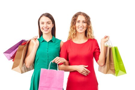 Portrait of two female friends holding multi-colored shopping bagsの写真素材