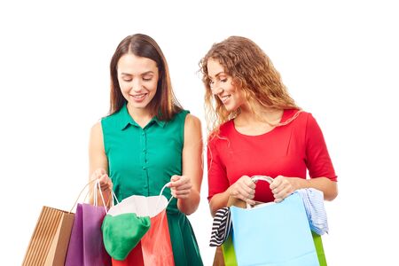 Portrait of two female friends holding multi-colored shopping bagsの写真素材