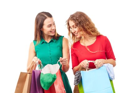 Portrait of two female friends holding multi-colored shopping bagsの写真素材