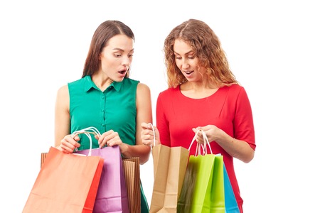 Portrait of two female friends holding multi-colored shopping bagsの写真素材