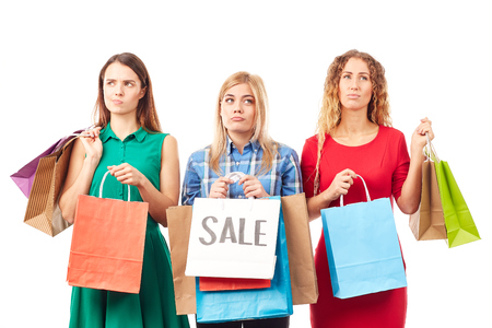 Portrait of three young woman holding bunches of multi-colored shopping bags after saleの写真素材
