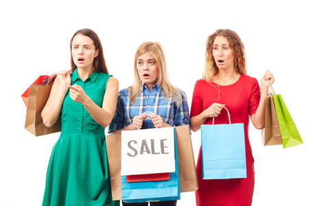 Portrait of three young woman holding bunches of multi-colored shopping bags after saleの写真素材