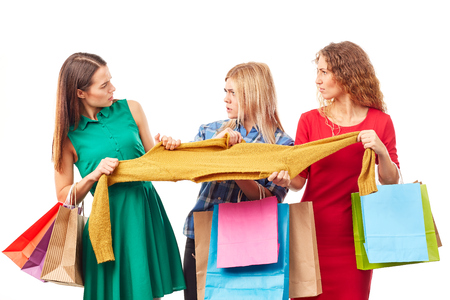 Three shopaholic women fighting over sweater on Black Fridayの写真素材