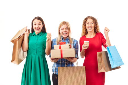 Portrait of three shopaholic girlfriends holding shopping bags and gift boxesの写真素材