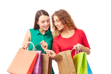 Portrait of two female friends holding multi-colored shopping bagsの写真素材
