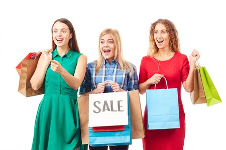 Portrait of three young woman holding bunches of multi-colored shopping bags after saleの写真素材