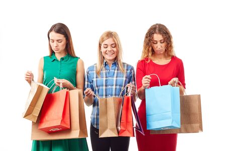 Portrait of three young girlfriends holding bunches of multi-colored shopping bagsの写真素材