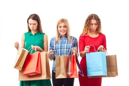 Portrait of three young girlfriends holding bunches of multi-colored shopping bagsの写真素材