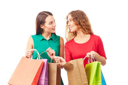 Portrait of two female friends holding multi-colored shopping bagsの写真素材