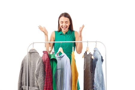Young woman choosing clothes on rack on white backgroundの写真素材