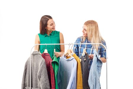 Two girlfriends choosing clothes on rackの写真素材