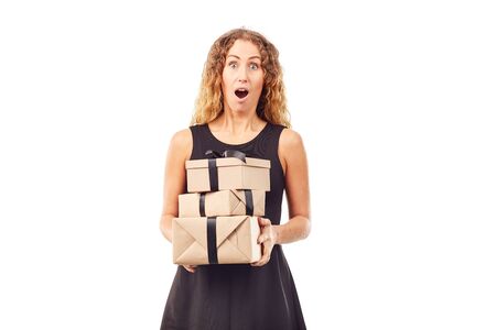 Portrait of curly-haired woman in black dress holding stack of gift boxes with black ribbonの写真素材