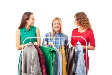 Three young woman browsing through clothes on rackの写真素材
