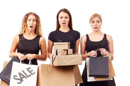 Portrait of three young women in black holding many shopping bagsの写真素材