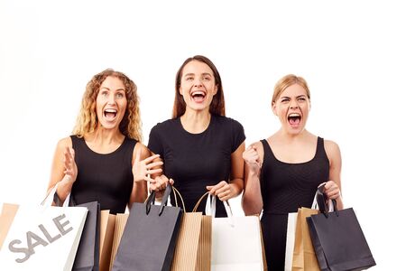 Portrait of three young women in black holding many shopping bagsの写真素材
