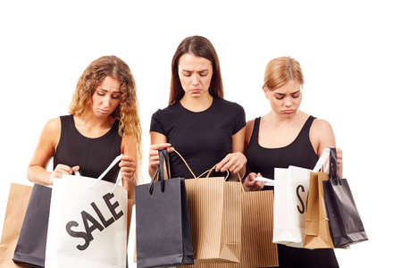 Portrait of three young women in black holding many shopping bagsの写真素材