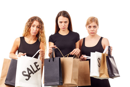 Portrait of three young women in black holding many shopping bagsの写真素材
