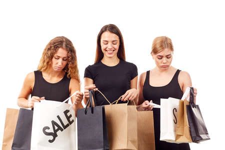 Portrait of three young women in black holding many shopping bagsの写真素材