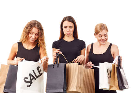 Portrait of three young women in black holding many shopping bagsの写真素材