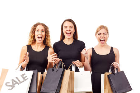 Portrait of three young women in black holding many shopping bagsの写真素材