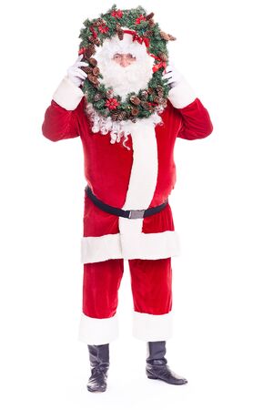 Portrait of Santa Claus in traditional costume holding Christmas wreathの写真素材