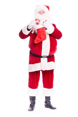 Portrait of Santa Claus hiding gift box into Christmas stocking on white backgroundの写真素材