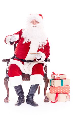 Portrait of Santa Claus sitting in chair, eating cookies and drinking milk isolated on whiteの写真素材
