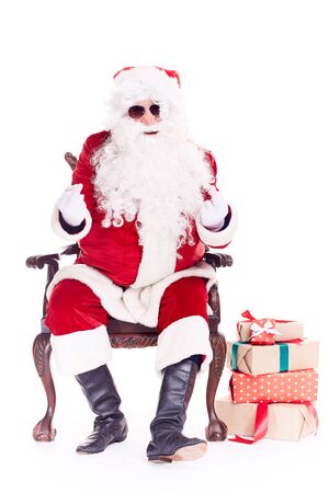 Portrait of swaggy Santa Claus in sunglasses relaxing in chair on white backgroundの写真素材