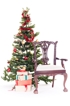Empty chair near Christmas tree and stack of gift boxes on white backgroundの写真素材