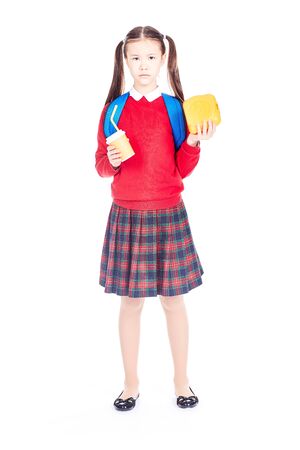 Portrait of Asian schoolgirl in uniform holding lunchbox and paper cup with drinking strawの写真素材