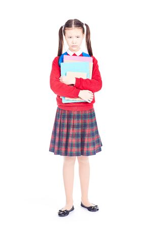 Portrait of female elementary student in school uniform holding notebooks and textbooksの写真素材