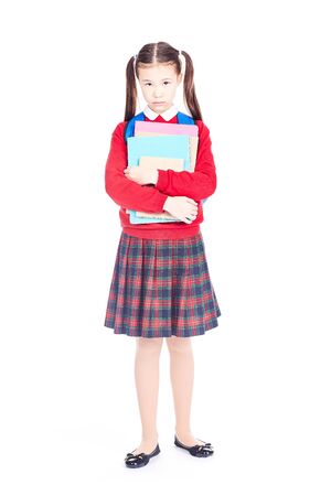 Portrait of female elementary student in school uniform holding notebooks and textbooksの写真素材