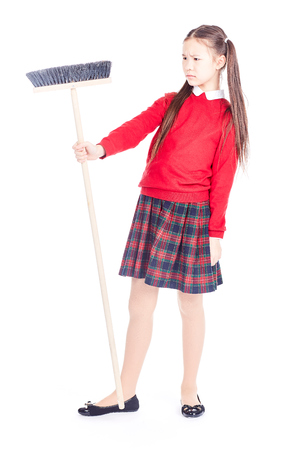 Portrait of girl in school uniform holding broom on white backgroundの写真素材