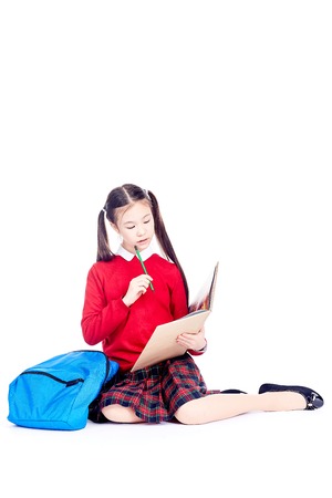Portrait of female Asian elementary student sitting on floor and doing homeworkの写真素材