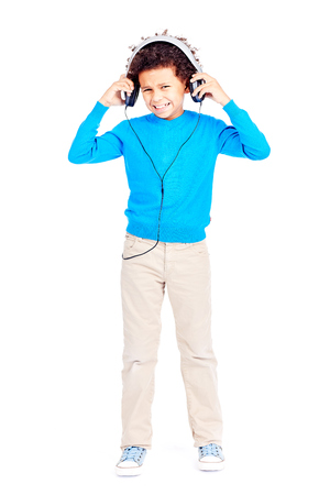Portrait of cute curly-haired Latin American boy annoyed with music in his headphonesの写真素材