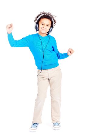 Portrait of cute curly-haired Latin American boy listening to music through earphones and dancingの写真素材